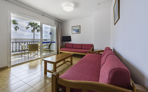 Bright one-bedroom apartment lounge opening onto a sea-view balcony